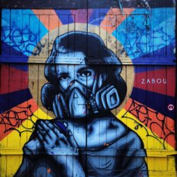 graffiti of a woman in a gas mask, hands held to chest